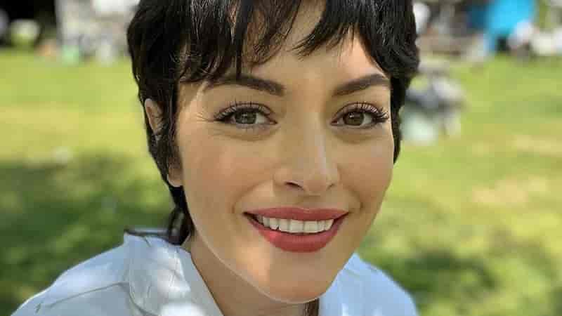 Big transfer Ezgi Mola from Şahmaran to Disney Plus's new series Ayten-min face close up of ezgi mola smiling, with short dark hair and red lips, wearing a white t-shirt ayten