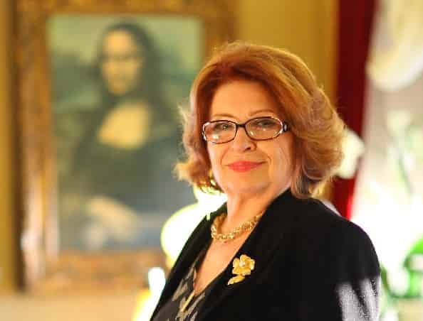 psychiatrist dr Gülseren Budaıcıoğlu wearing glasses with a black jacket stading in front of Monalisa