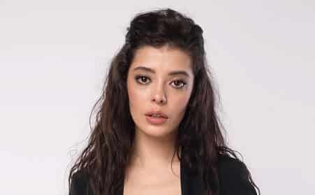 Kraliçe The Queen (2023) Gökhan Alkan and Burcu Özberk New Turkish Dizi Series Kanal D 1-min Selin Şekerci with curly hair wearing a black jacket on a white background