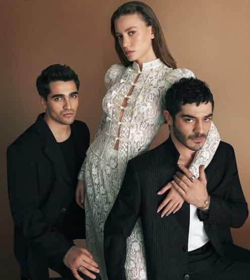 Shahmaran Top 10 Facts Turkish Series Burak Deniz, Serenay Sarıkaya and Mert Ramazan Demir Netflix 1-min leading actors of Shahmaran series on netflix, Burak Deniz wearing black suit in front of Serenay Sarikaya who wears white dress, and keeps her hand on him with Mert Ramazan Demir wearing black suit behind her