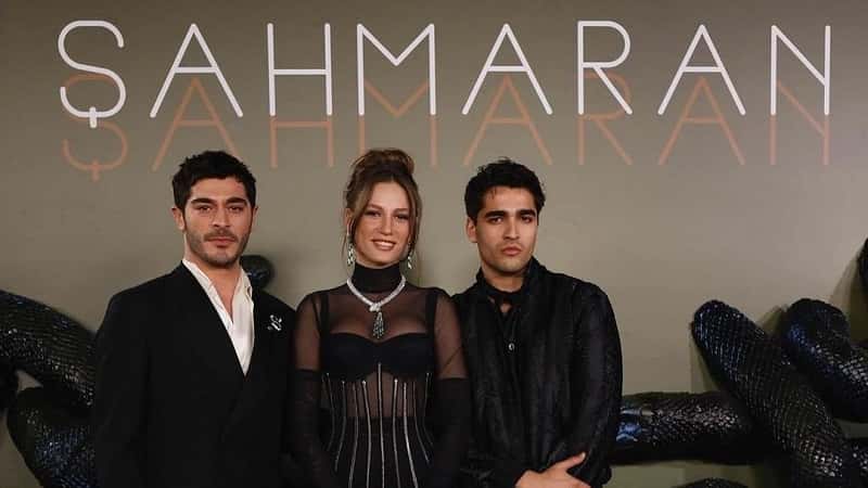 Shahmaran Top 10 Facts Turkish Series Burak Deniz, Serenay Sarıkaya and Mert Ramazan Demir Netflix 2-min Burak Deniz wearing black suit next to Serenay Sarikaya who wears a black dress with a snake necklance and Mert Ramazan Demir wearing black suit, at the premiere of Shahmaran series on netflix