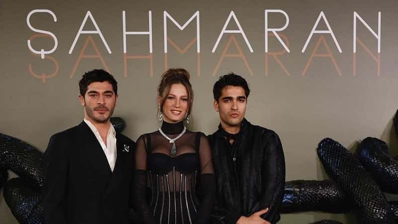 Burak Deniz wearing black suit next to Serenay Sarikaya who wears a black dress with a snake necklance and Mert Ramazan Demir wearing black suit, at the premiere of Shahmaran series on netflix