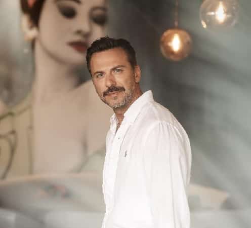 turkish actor Serkan Altunorak wearing white shirt with a woman on the background in the turkish new dizi series Bergüzar Korel Kanlı Yayın Caner Cindoruk