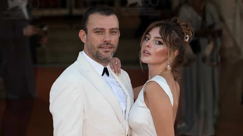 Salih Bademci and Melis Sezen Venice Film Festival-min Salih Bademci wearing a white suit next to Melis Sezen wearing a white dress with back crop on red carper the Venice Film Festival